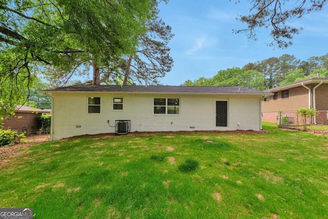 back of house featuring brick siding, a lawn, fence, and crawl space