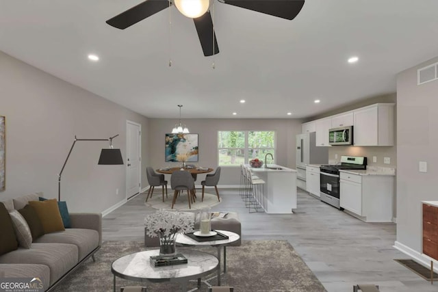 living room featuring recessed lighting, baseboards, visible vents, and light wood-style flooring