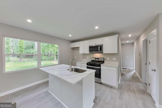kitchen featuring baseboards, white cabinets, a sink, light wood-style flooring, and stainless steel appliances