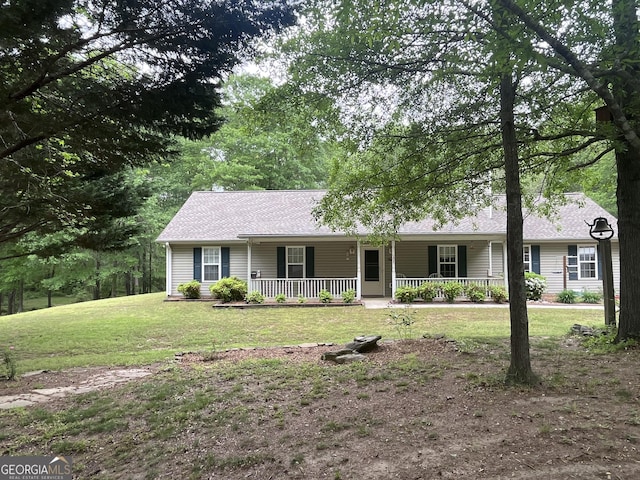 ranch-style home with covered porch, a shingled roof, and a front yard