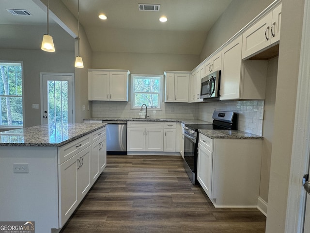 kitchen featuring visible vents, a kitchen island, white cabinets, a sink, and stainless steel appliances