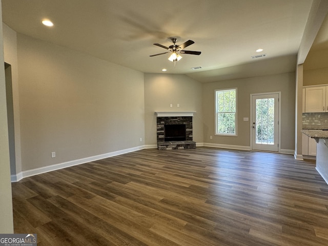 unfurnished living room with ceiling fan, dark wood-style floors, baseboards, and a fireplace