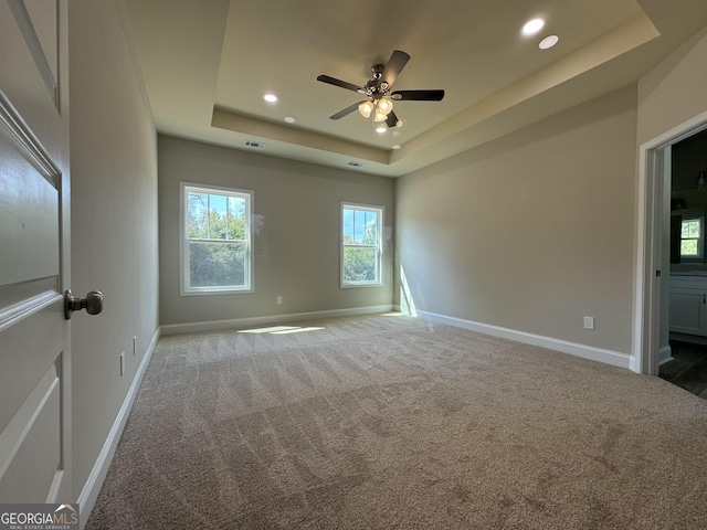 unfurnished bedroom with recessed lighting, carpet flooring, and a tray ceiling