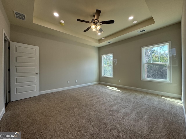 unfurnished room featuring baseboards, a tray ceiling, and visible vents