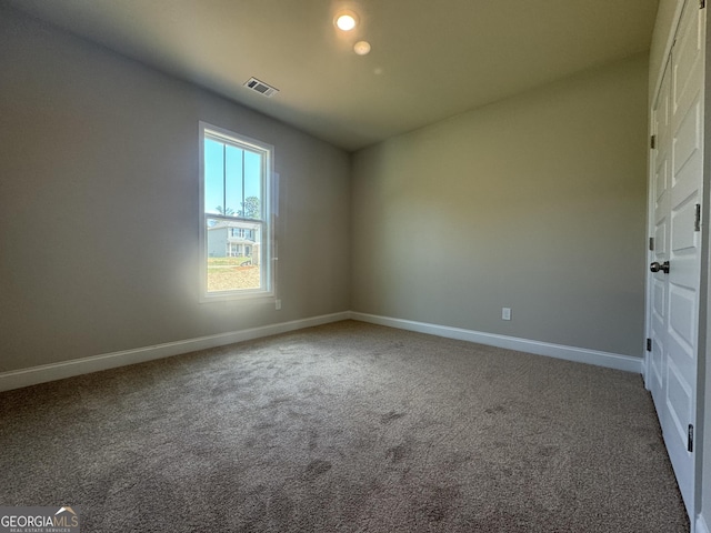 spare room with carpet floors, baseboards, and visible vents