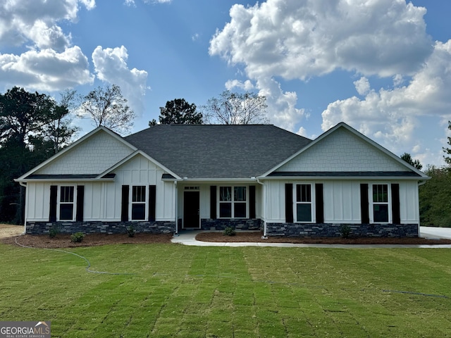 craftsman house featuring roof with shingles, board and batten siding, and a front yard