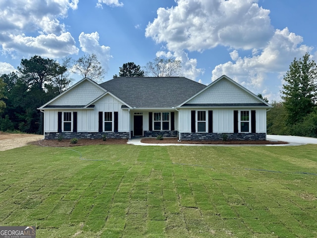 view of front of house with board and batten siding, a front yard, and stone siding