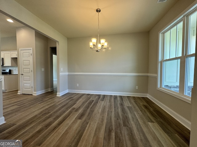 unfurnished dining area with baseboards, recessed lighting, a notable chandelier, and dark wood-style floors