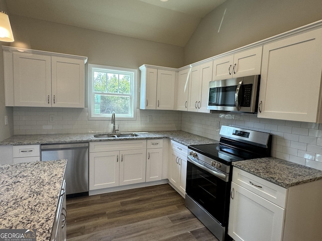 kitchen with dark wood finished floors, a sink, lofted ceiling, stainless steel appliances, and white cabinetry