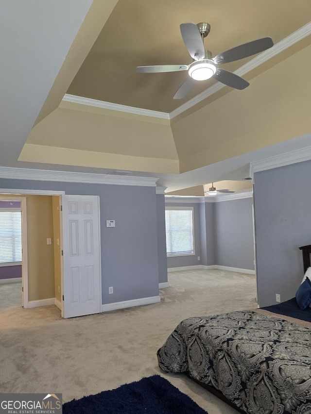 carpeted bedroom featuring crown molding, a raised ceiling, baseboards, and ceiling fan