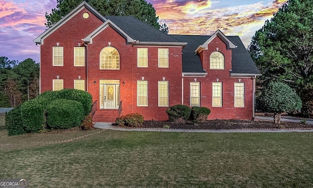 colonial-style house featuring brick siding and a lawn