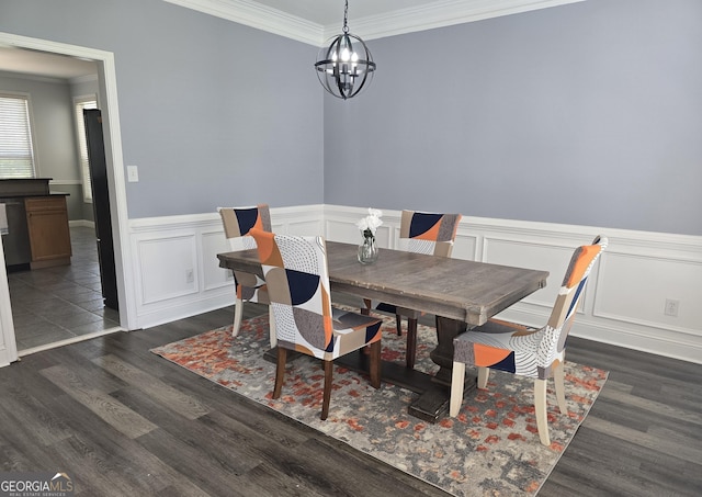 dining room with a chandelier, crown molding, a wainscoted wall, and wood finished floors