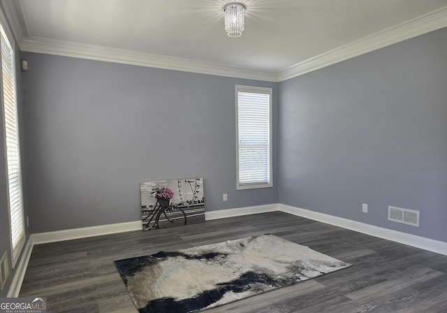 spare room with dark wood finished floors, a wealth of natural light, visible vents, and ornamental molding