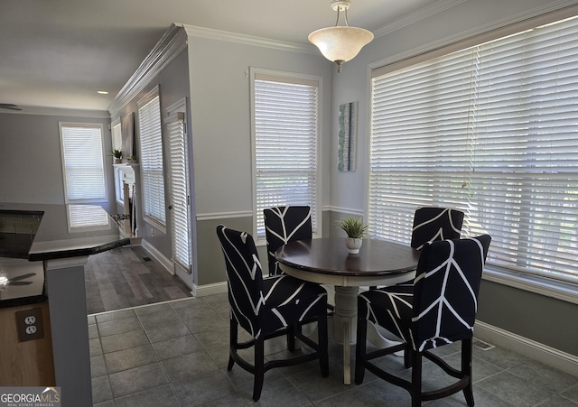 dining room featuring baseboards, ornamental molding, and dark tile patterned floors