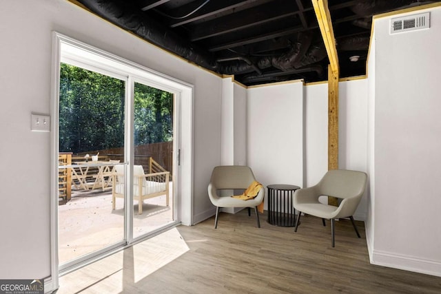 sitting room with baseboards, visible vents, and wood finished floors