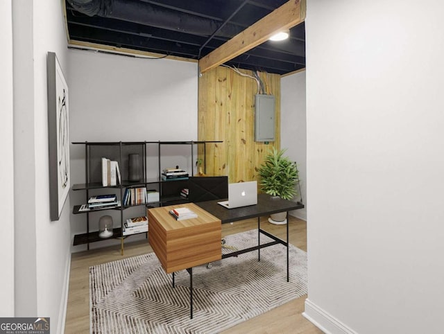 office featuring baseboards, wooden walls, wood finished floors, and electric panel
