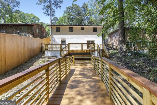 back of property featuring brick siding, a wooden deck, stairway, and fence