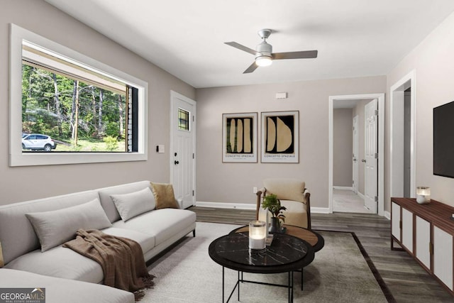 living area featuring a ceiling fan, baseboards, and wood finished floors
