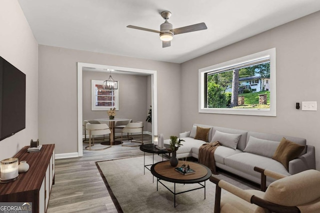 living room with baseboards, ceiling fan, and light wood-type flooring