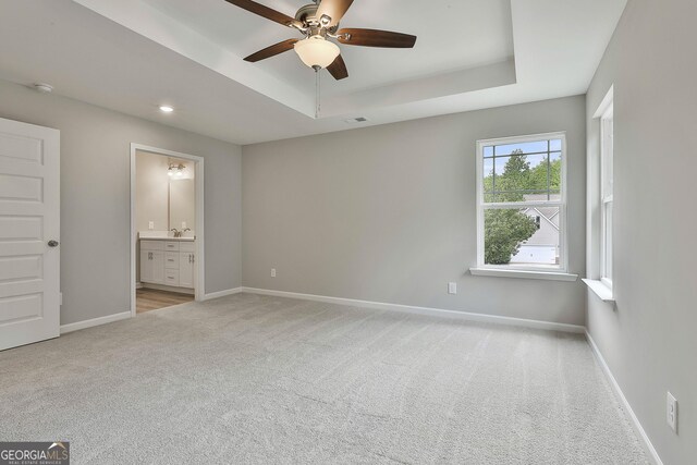 51 Camden Cir, Newnan, GA 30265 - unfurnished bedroom featuring light carpet, ensuite bath, baseboards, a tray ceiling, and visible vents