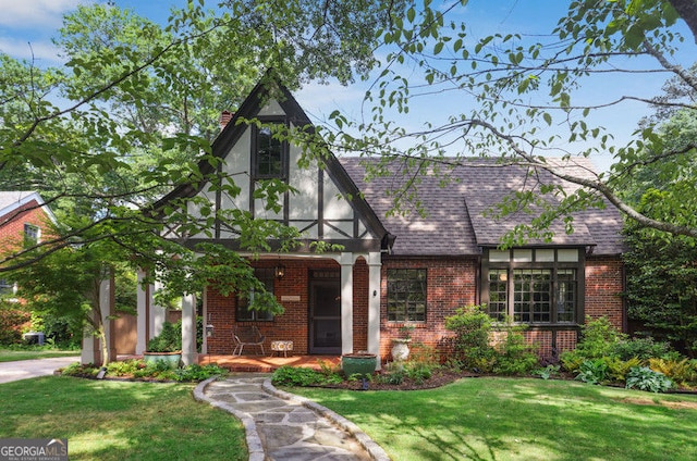 26 Clarendon Ave, Avondale Estates, GA 30002 - tudor-style house with covered porch, brick siding, a shingled roof, and a front lawn
