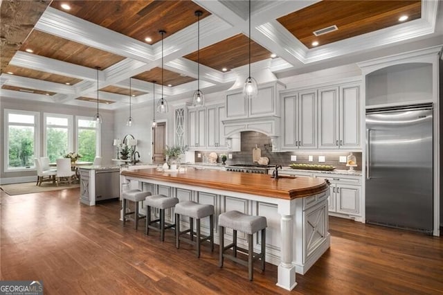1101 N Flat Rock Rd, Douglasville, GA 30134 - kitchen featuring butcher block counters, an island with sink, dark wood-style floors, coffered ceiling, and stainless steel built in refrigerator