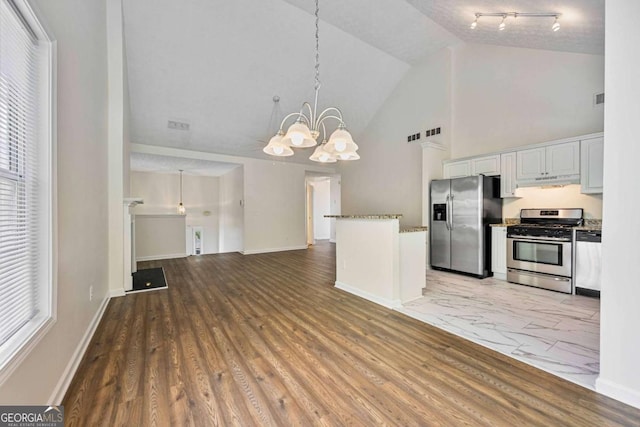 5135 Gable Ridge Way, Sugar Hill, GA 30518 - kitchen featuring open floor plan, high vaulted ceiling, under cabinet range hood, a chandelier, and appliances with stainless steel finishes