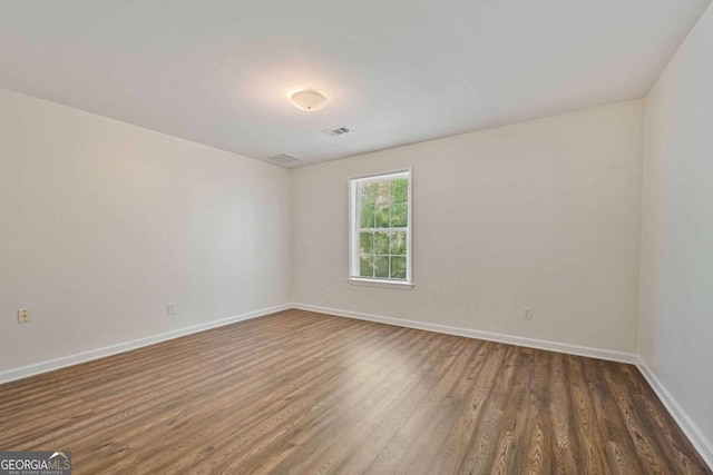 empty room with baseboards, visible vents, and dark wood-type flooring