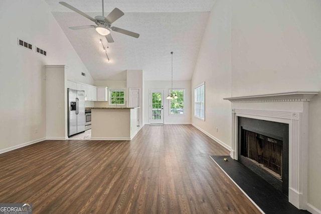 unfurnished living room featuring dark wood-style flooring, high vaulted ceiling, baseboards, and ceiling fan with notable chandelier