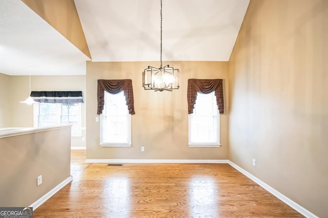 1008 Walnut Creek Dr, Woodstock, GA 30188 - unfurnished dining area with an inviting chandelier, baseboards, wood finished floors, lofted ceiling, and visible vents