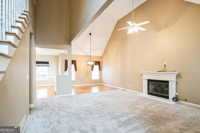 1008 Walnut Creek Dr, Woodstock, GA 30188 - unfurnished living room with high vaulted ceiling, baseboards, ceiling fan with notable chandelier, a glass covered fireplace, and carpet