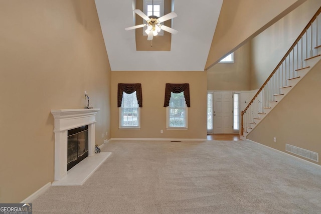 1008 Walnut Creek Dr, Woodstock, GA 30188 - unfurnished living room featuring a ceiling fan, visible vents, high vaulted ceiling, a glass covered fireplace, and stairs