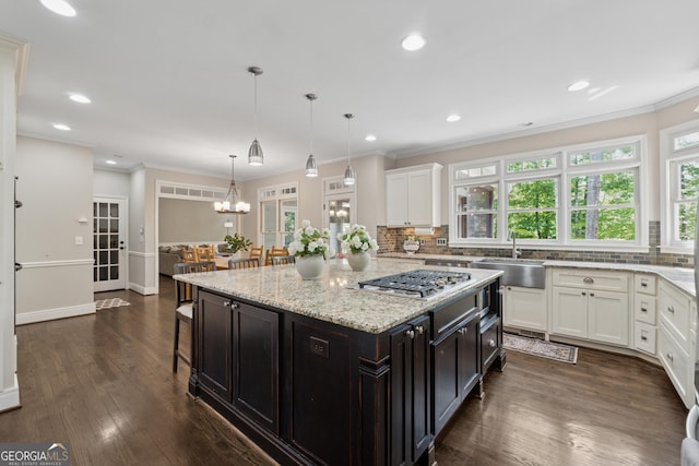 kitchen featuring a sink, decorative backsplash, white cabinets, and stainless steel gas cooktop