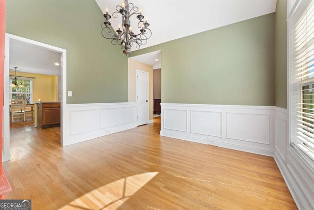 4572 Mulberry Fields Ln, Auburn, GA 30011 - unfurnished dining area featuring light wood-style floors, wainscoting, a decorative wall, and a notable chandelier