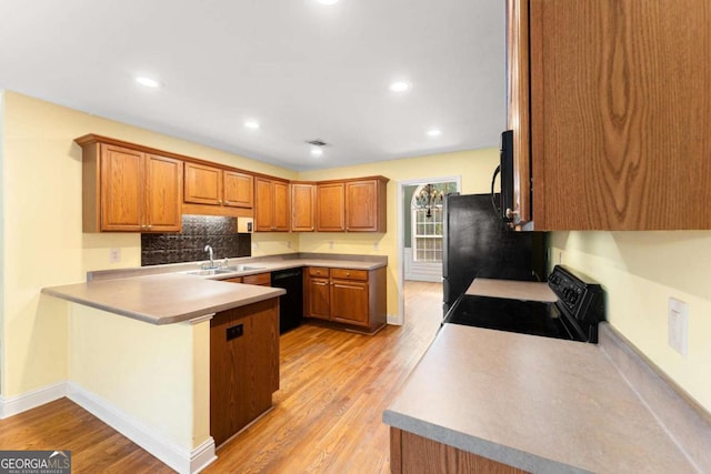 4572 Mulberry Fields Ln, Auburn, GA 30011 - kitchen with a peninsula, tasteful backsplash, black appliances, and light wood-style floors