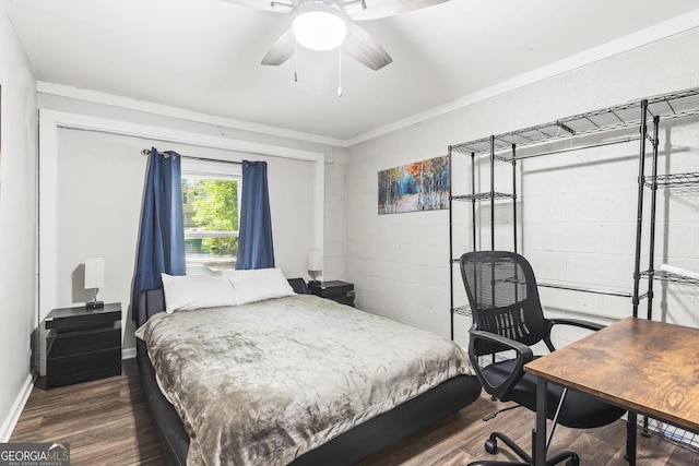 bedroom featuring concrete block wall, crown molding, a ceiling fan, and dark wood-style flooring