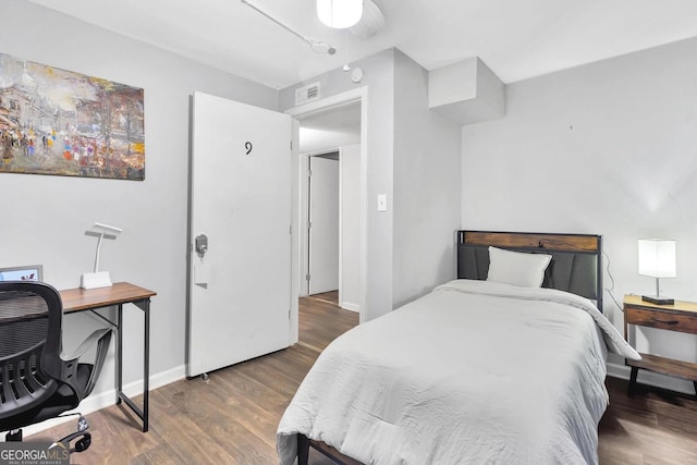 bedroom featuring baseboards, visible vents, and wood finished floors