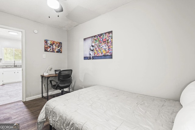 bedroom featuring ceiling fan, a sink, baseboards, ensuite bathroom, and dark wood-style floors