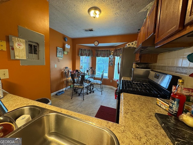 6444 Charter Way, Lithonia, GA 30058 - kitchen with visible vents, baseboards, gas range, brown cabinets, and tasteful backsplash