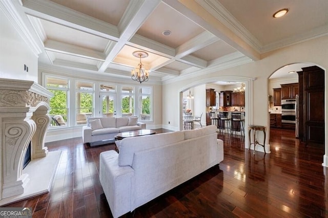 living area featuring dark wood-type flooring, arched walkways, beam ceiling, and a chandelier