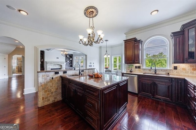 kitchen featuring stainless steel dishwasher, arched walkways, and a sink