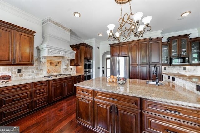 kitchen featuring an inviting chandelier, premium range hood, a sink, appliances with stainless steel finishes, and hanging light fixtures