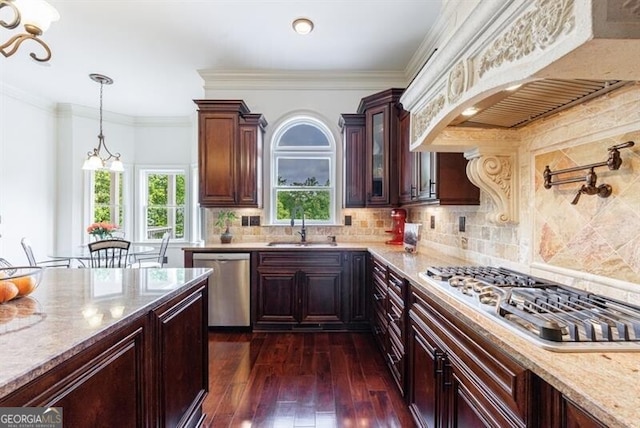 kitchen with custom range hood, appliances with stainless steel finishes, light stone countertops, and glass insert cabinets