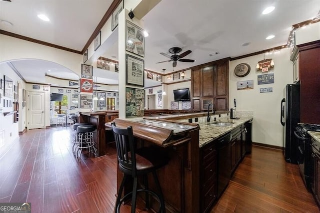 kitchen featuring ceiling fan, crown molding, light stone countertops, a sink, and black appliances