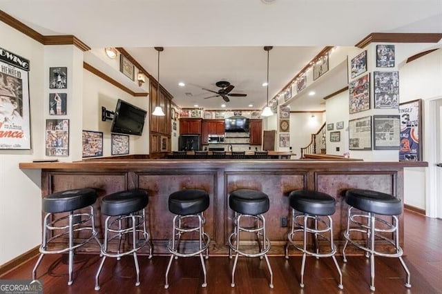 bar featuring a ceiling fan, a dry bar, baseboards, stainless steel microwave, and dark wood-type flooring