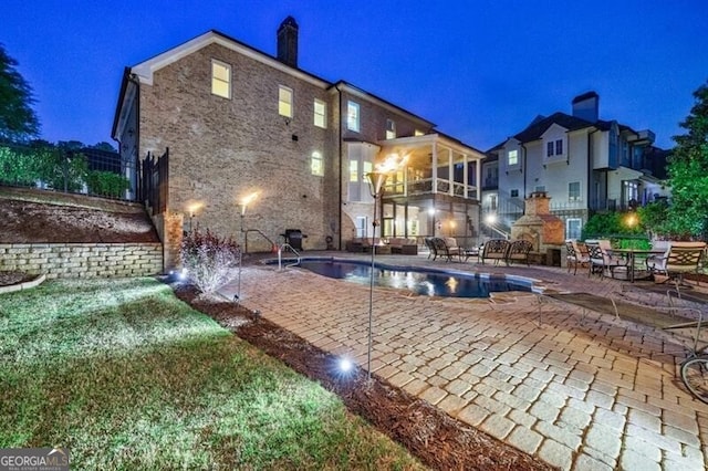 pool at twilight featuring a patio and an outdoor pool