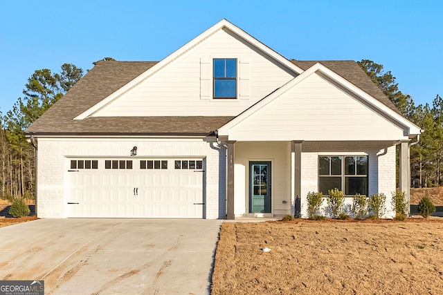 traditional-style home featuring roof with shingles, covered porch, driveway, and brick siding