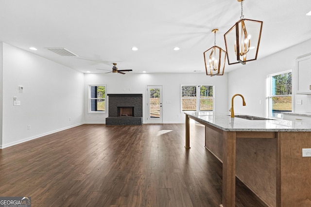 kitchen featuring a brick fireplace, recessed lighting, visible vents, and a sink