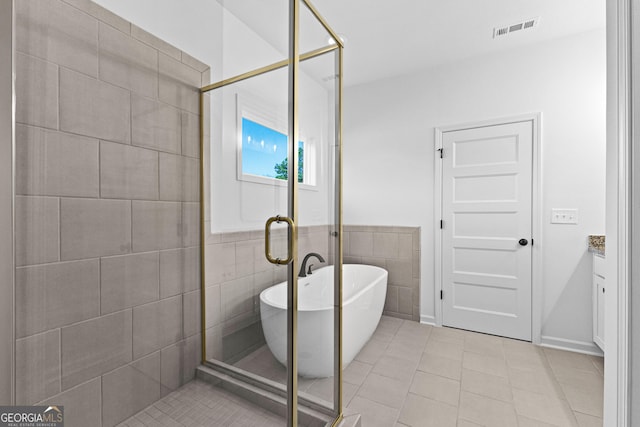 full bath featuring a freestanding bath, tile patterned floors, tile walls, visible vents, and a stall shower
