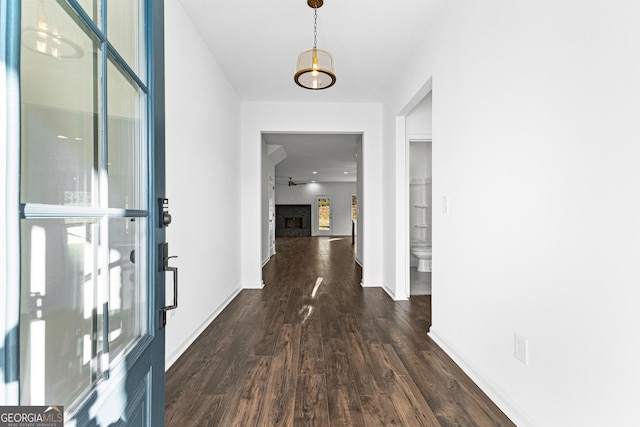 hallway featuring baseboards and dark wood-style flooring